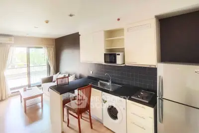 Modern open-layout kitchen with washing machine and cozy living area, featuring natural light and stylish decor.