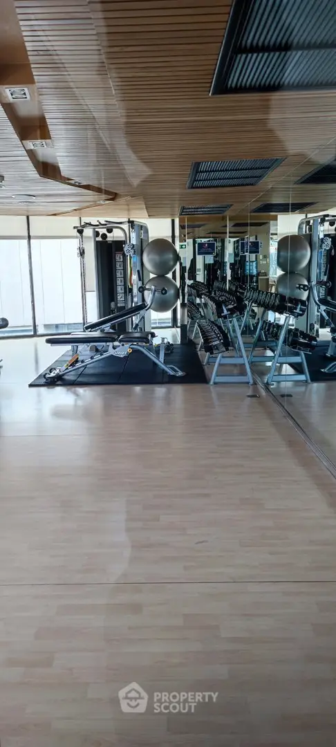 Modern gym with state-of-the-art equipment and mirrored walls in luxury residential building.