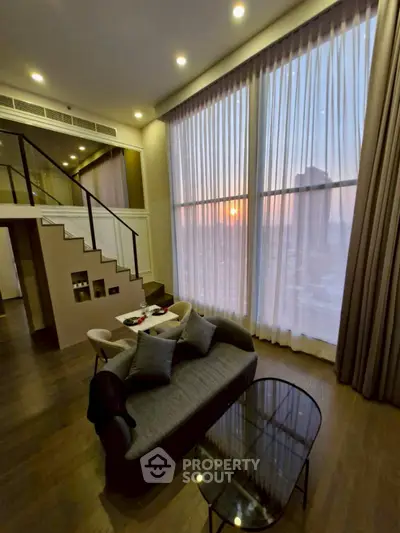 Luxurious duplex living room with floor-to-ceiling windows and stunning sunset view.