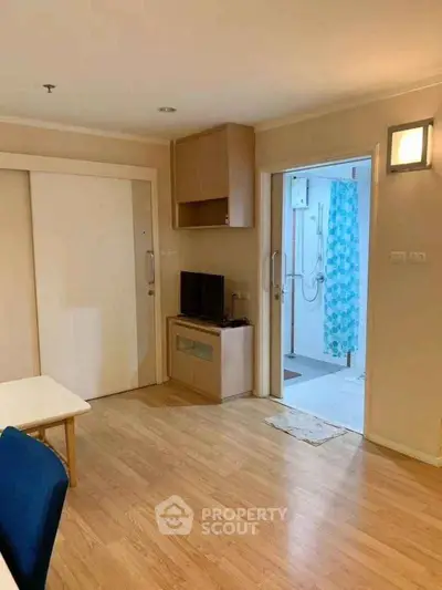 Cozy apartment interior with wooden flooring and modern bathroom access.