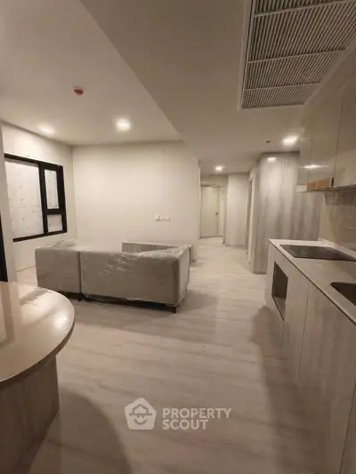 Modern open-layout living room with sleek kitchen and cozy seating area.