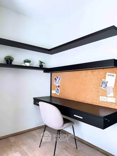 Modern study room with sleek black desk, corkboard, and floating shelves for a stylish workspace.