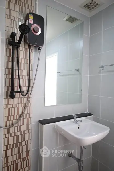 Modern bathroom with sleek shower and basin in stylish tiled setting.