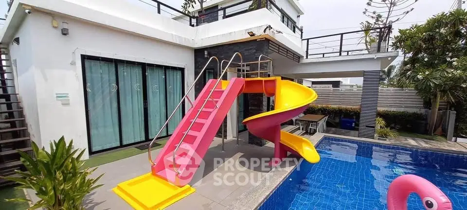 Luxurious modern villa with vibrant slide and pool, perfect for family fun and relaxation.
