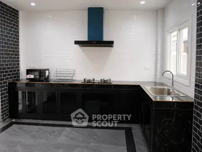 Modern kitchen with sleek black cabinetry and gas stove, featuring a stylish open layout and elegant tile backsplash.