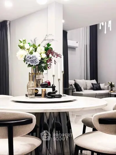 Elegant modern dining area with chic decor and cozy living room in open layout apartment.