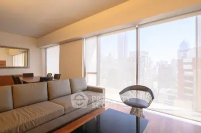 Spacious modern living room with city view, featuring elegant furniture and large windows.