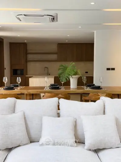 Luxurious open-plan living room with modern kitchen, elegant dining area, and plush white sofa.