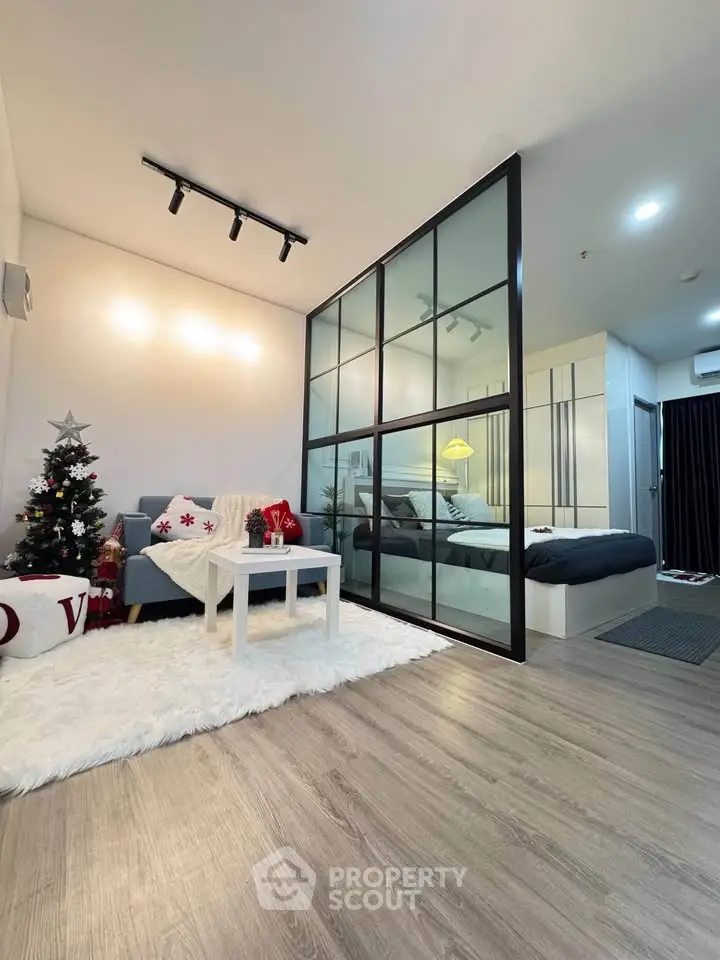 Modern studio apartment with glass partition, cozy living area, and festive decor.