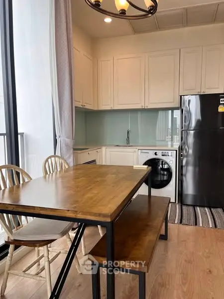 Modern kitchen with dining area, featuring wooden table, chairs, and built-in appliances.