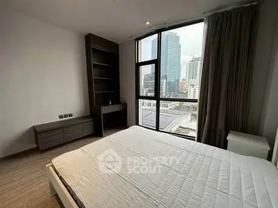 Modern bedroom with large window and city view, featuring sleek furniture and natural light.