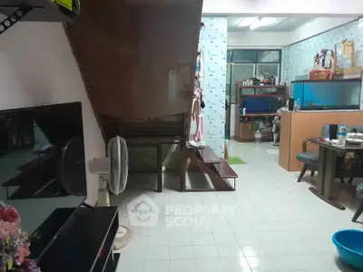 Cozy living area with staircase and dining space, featuring tiled flooring and modern decor.