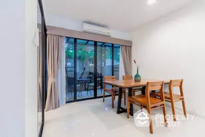 Modern dining area with wooden table and chairs, sliding glass doors to patio