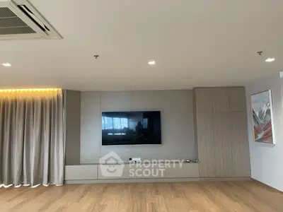 Spacious modern living room with mounted TV and elegant wood flooring.