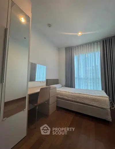 Cozy bedroom with modern furnishings and large window for natural light.
