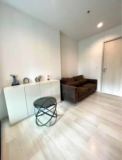 Modern living room with sleek furniture and minimalist decor, featuring a cozy brown sofa and stylish glass table.