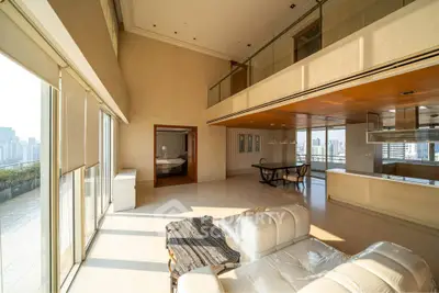 Luxurious high-ceiling living room with city view and modern open kitchen design.