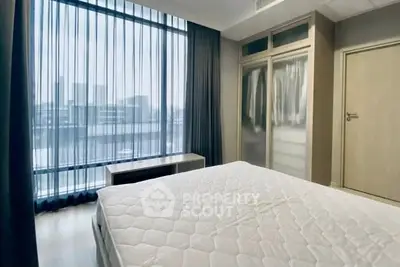 Modern bedroom with large window and city view, featuring a comfortable bed and stylish wardrobe.