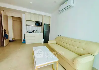 Modern living room with beige sofa, marble coffee table, and compact kitchen area.
