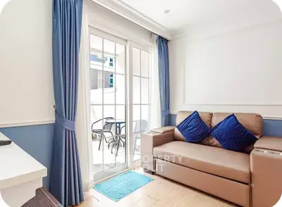 Charming living room with cozy sofa and elegant blue curtains leading to a bright balcony.