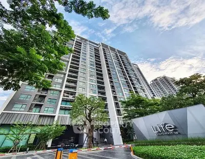 Modern high-rise condominium with lush greenery and clear sky view.