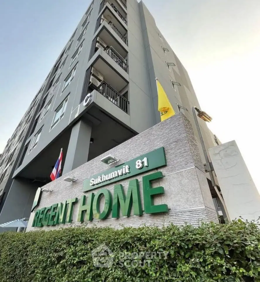 Modern condominium building exterior with flags and lush greenery at Regent Home Sukhumvit 81.