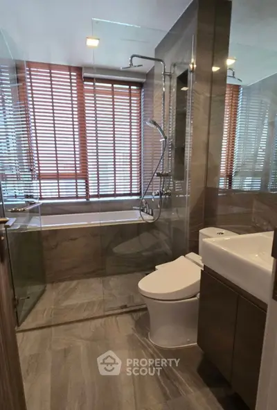 Modern bathroom with glass shower and bathtub, featuring sleek design and natural light.