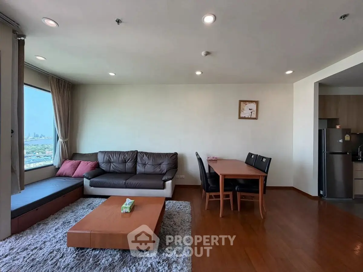 Spacious living room with city view, cozy seating, and dining area in modern apartment.