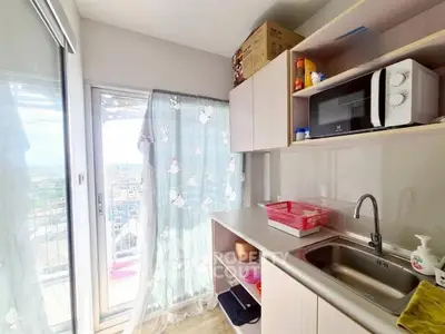 Cozy kitchen with balcony view, featuring modern microwave and ample storage space.