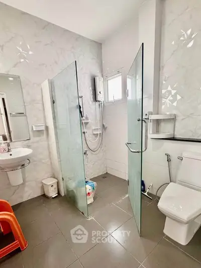 Modern bathroom with glass shower, sleek fixtures, and elegant tile design.