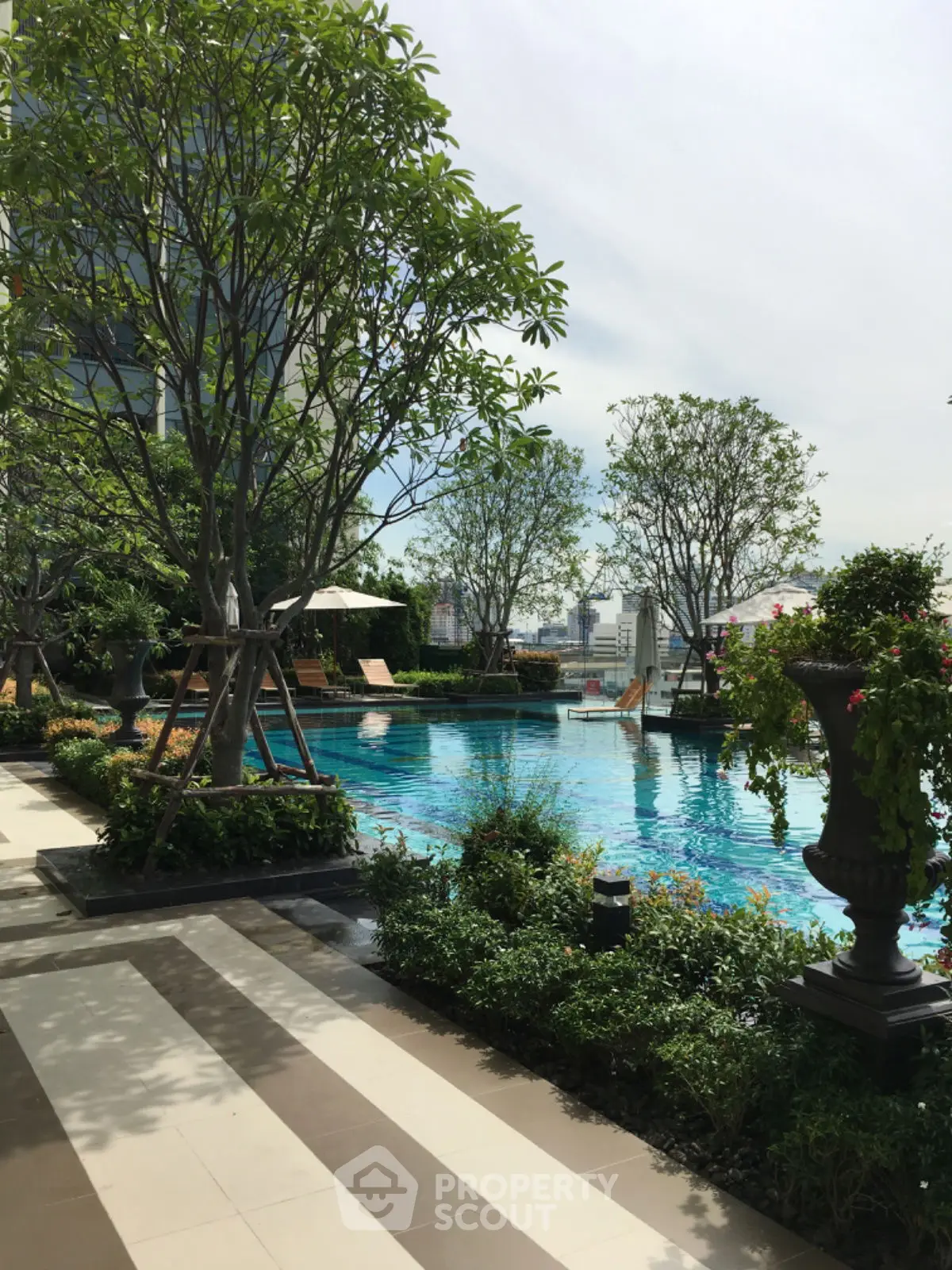 Luxurious rooftop pool with lush greenery and city views, perfect for relaxation and leisure.