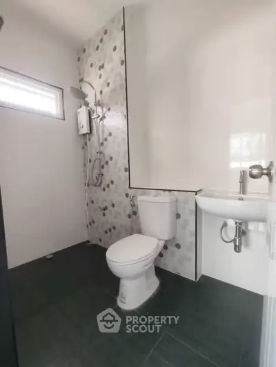 Modern bathroom with sleek design, featuring a shower, toilet, and sink in a compact layout.