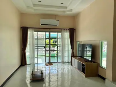 Spacious living room with modern decor and large windows leading to a balcony.