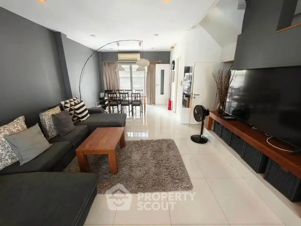 Spacious modern living room with sleek decor and large TV, perfect for relaxation and entertainment.