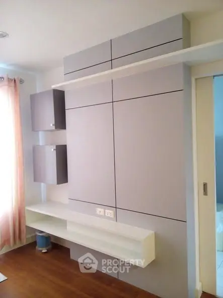 Modern minimalist living room with sleek built-in storage and elegant wood flooring.