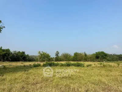 Expansive land plot with lush greenery and clear blue sky, perfect for development or investment.