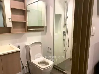 Modern bathroom with glass shower and sleek fixtures in contemporary apartment.