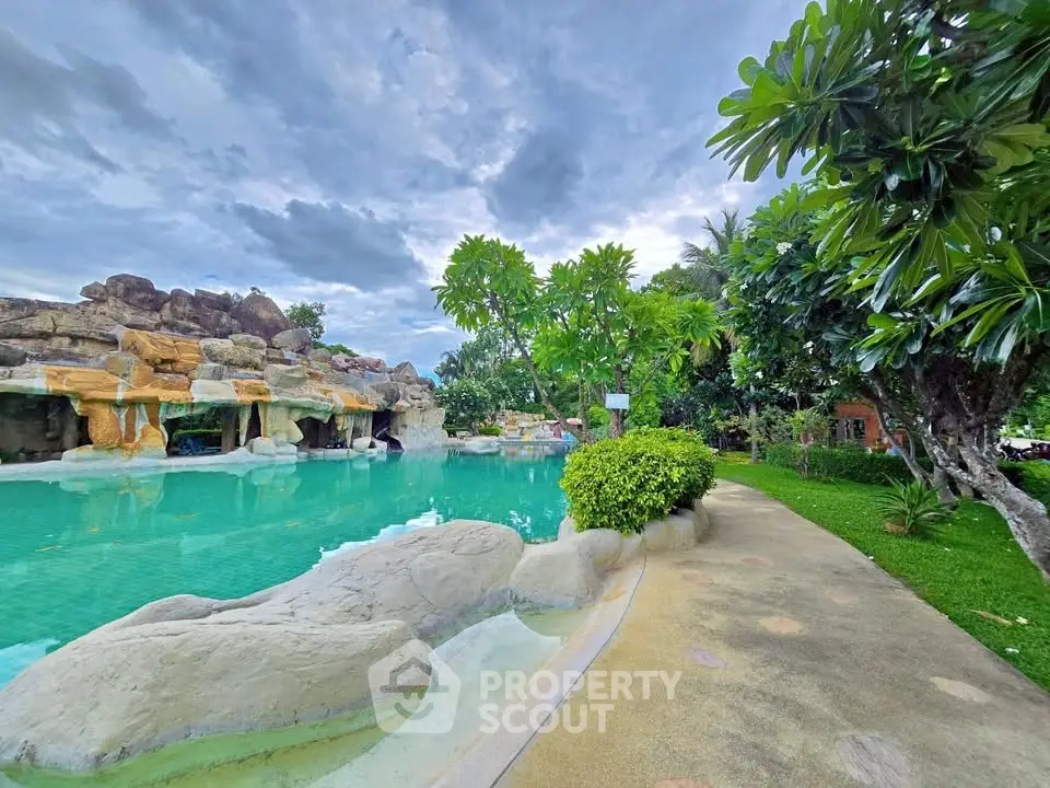 Luxurious resort-style pool with lush greenery and rock formations, perfect for relaxation and leisure.