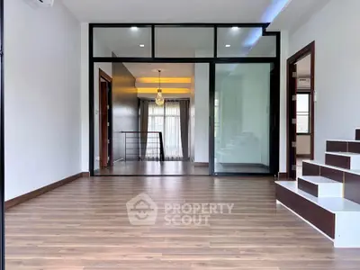Spacious modern living room with elegant wooden flooring and large glass doors.