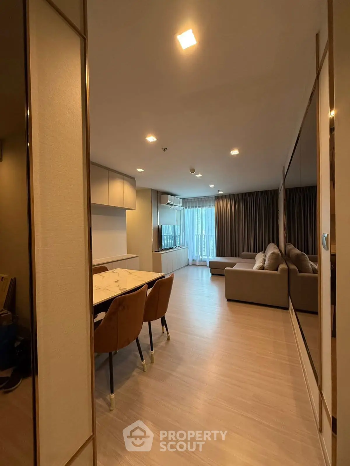 Modern living room with cozy sofa and dining area, featuring elegant lighting and large windows.