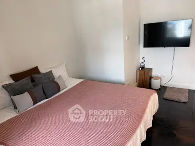 Cozy bedroom with modern decor and wall-mounted TV, perfect for relaxation.