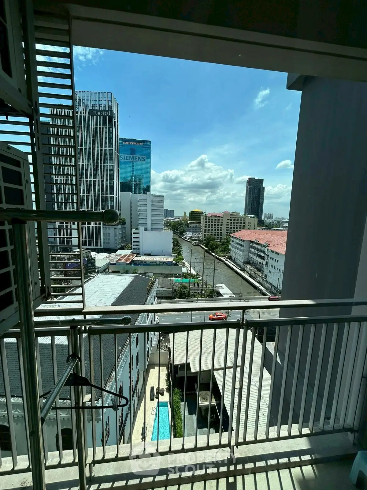 Stunning city view from high-rise balcony overlooking urban skyline and pool.