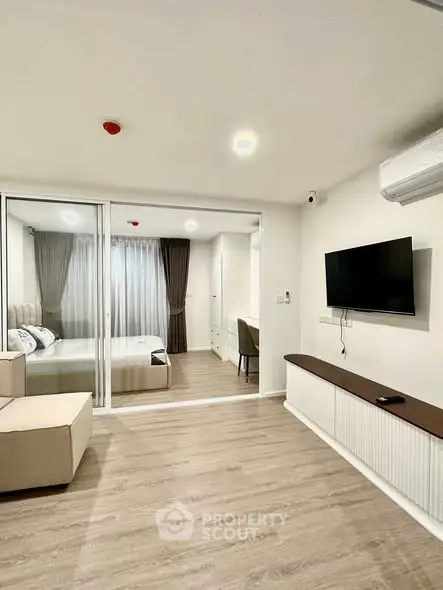 Modern living room with sliding glass doors leading to a cozy bedroom, featuring sleek furniture and ambient lighting.