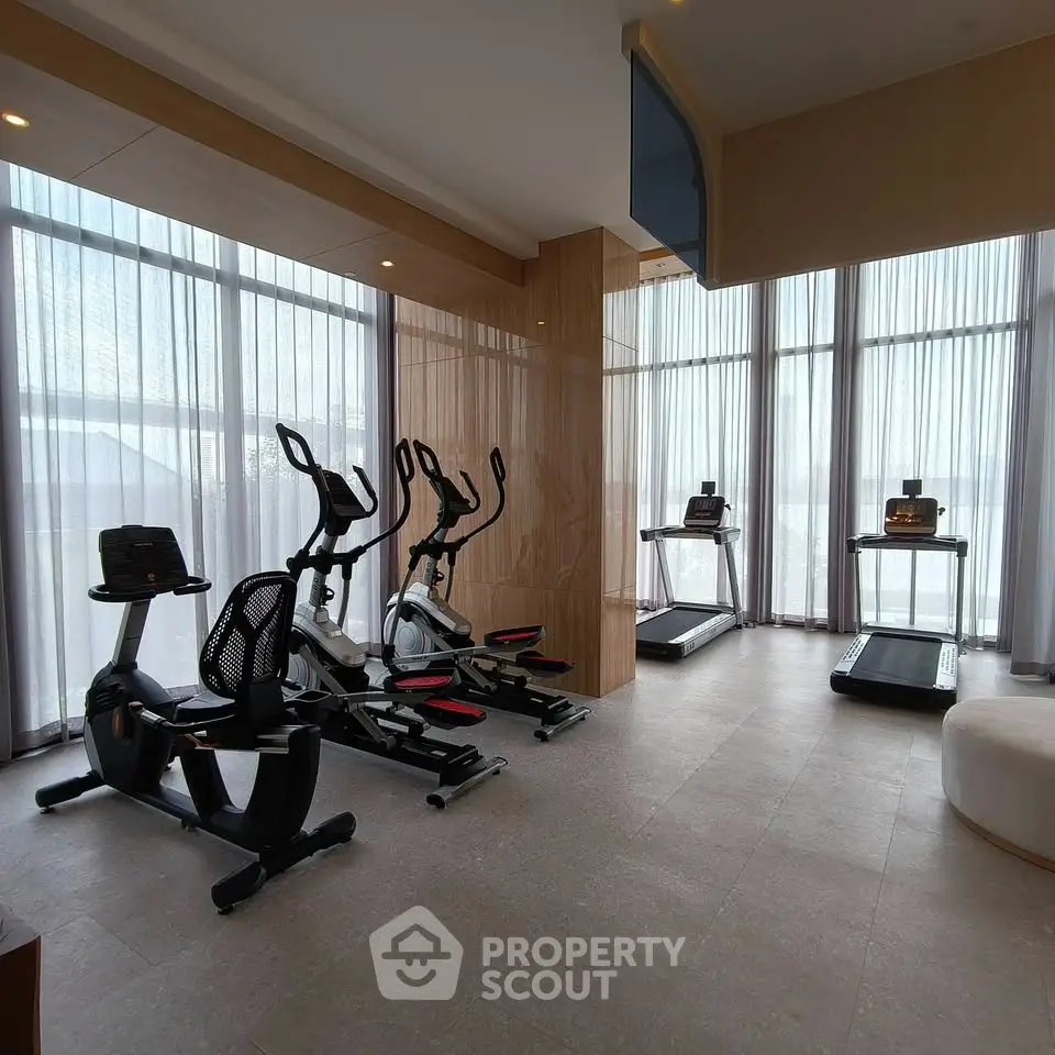 Modern gym with exercise bikes and treadmills in a well-lit space with large windows.