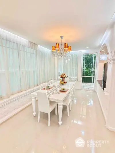 Elegant dining room with chandelier and large windows in a bright, modern home.