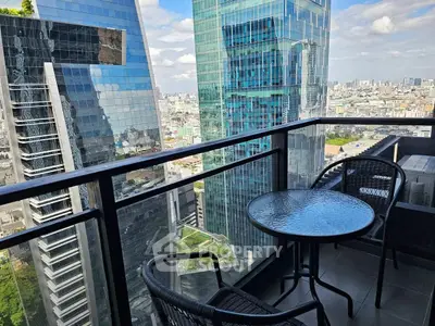 Stunning city view from a modern high-rise balcony with glass railing and outdoor seating.