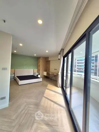 Spacious modern bedroom with large windows and balcony access in a high-rise apartment.