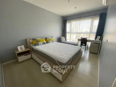 Modern bedroom with city view, featuring a cozy bed, desk, and large windows for natural light.