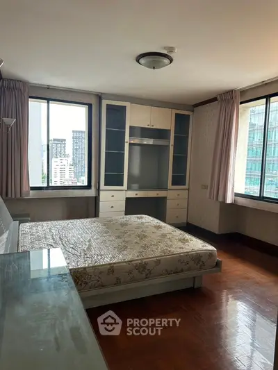 Spacious bedroom with large windows and built-in storage in urban apartment
