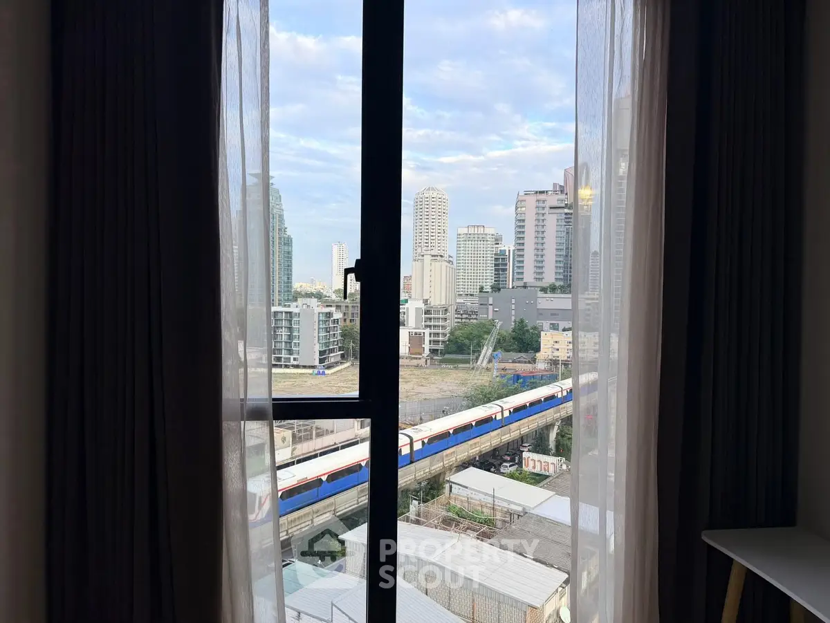 Stunning cityscape view from high-rise apartment window with train passing by